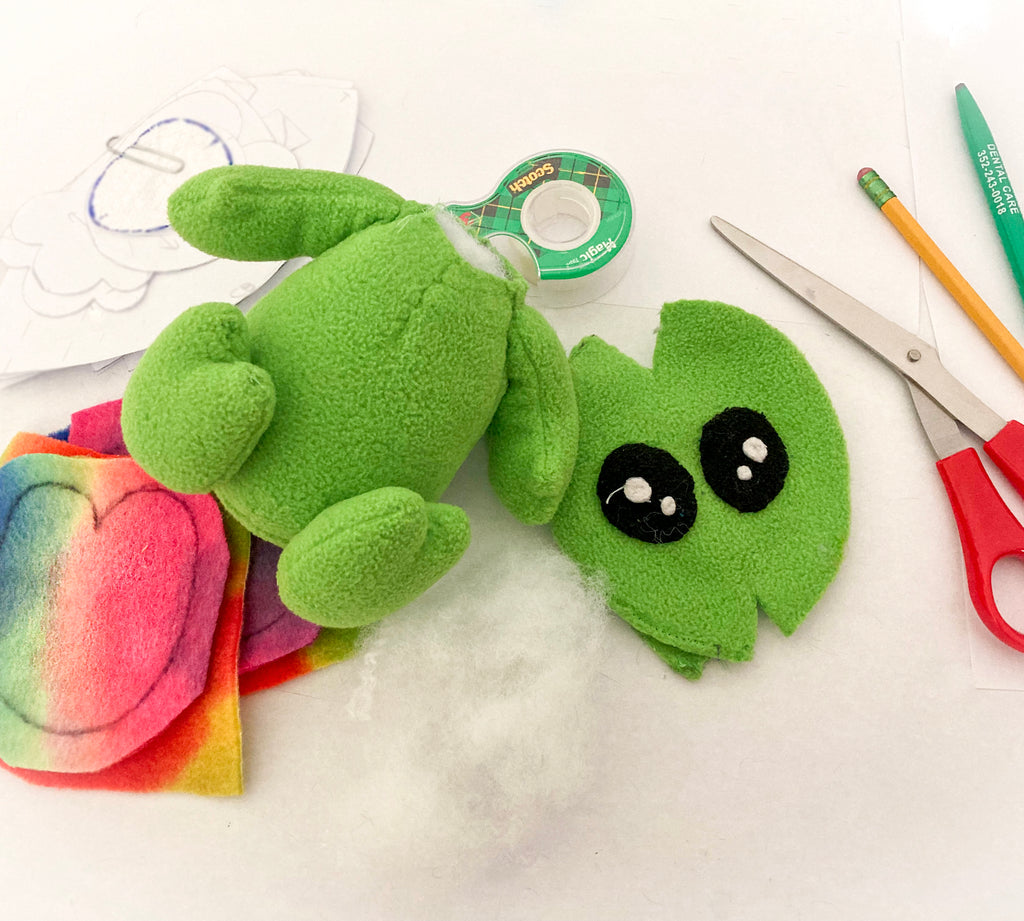 An alien plush and plush sewing pattern with craft supplies spread out.